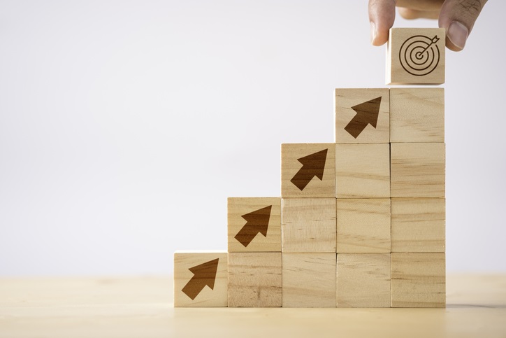 Building blocks ascending up, diagonally to the right, towards a bullseye