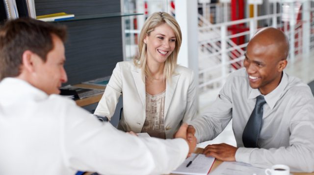 Male partners shaking hands after a business deal at desk