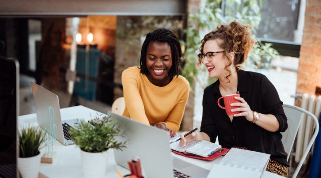 Two Businesswomen Working On Computer In Office