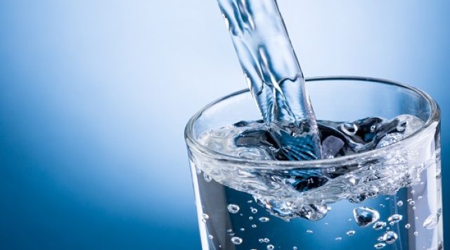 Pouring Water Into Glass On Blue Background