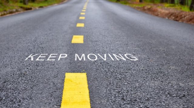 A road with yellow lines in the middle and the words "keep going"