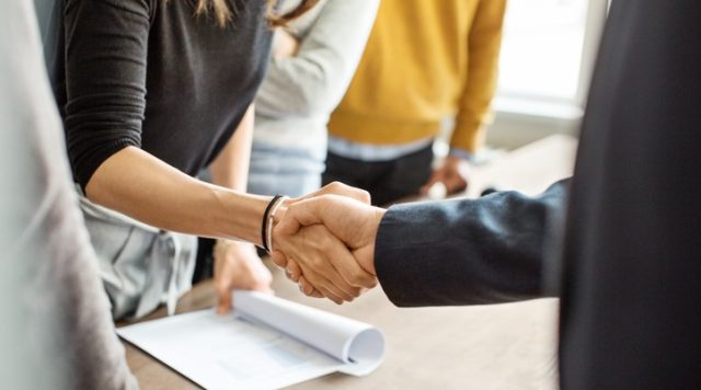 Two people shaking hands at a business deal